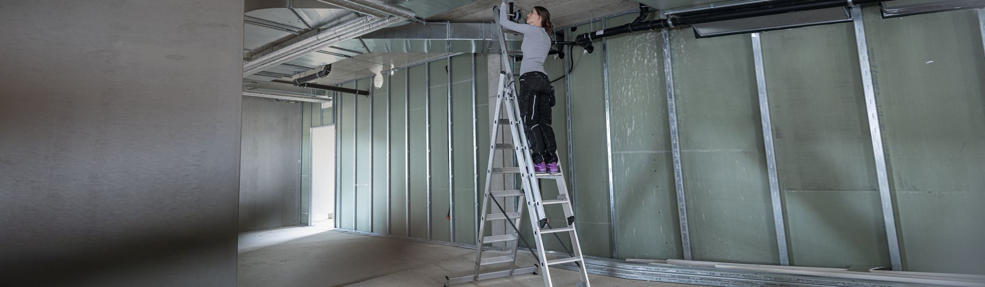 Handwerkerin auf einer Munk Günzburger Steigtechnik Mehrzweckleiter bild