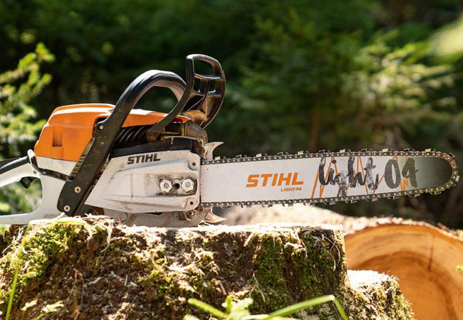 Produktbild Stihl Kettensäge auf einem Baumstumpf im Wald liegend