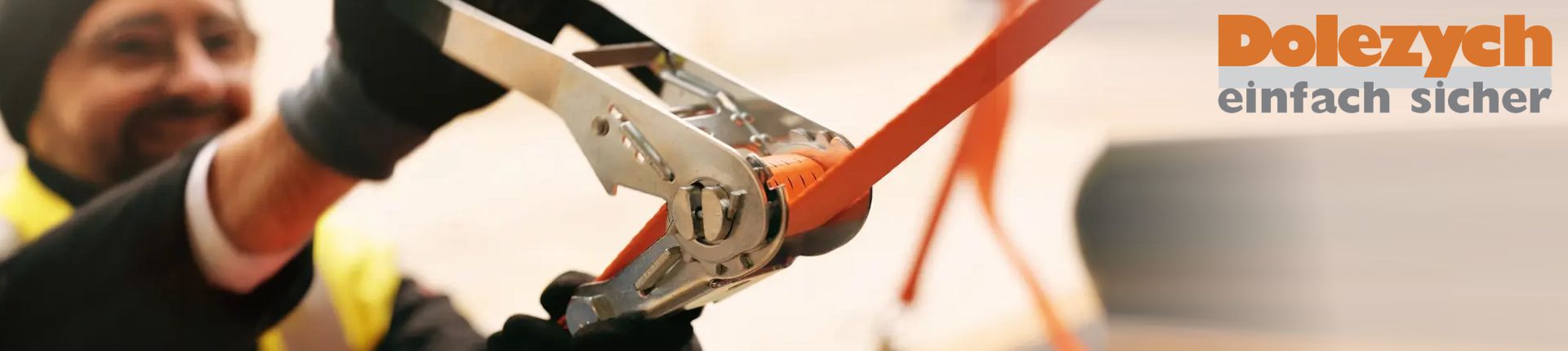 Bild Ein Mann spannt einen orangefarbenen Zurrgurt von Dolezych an