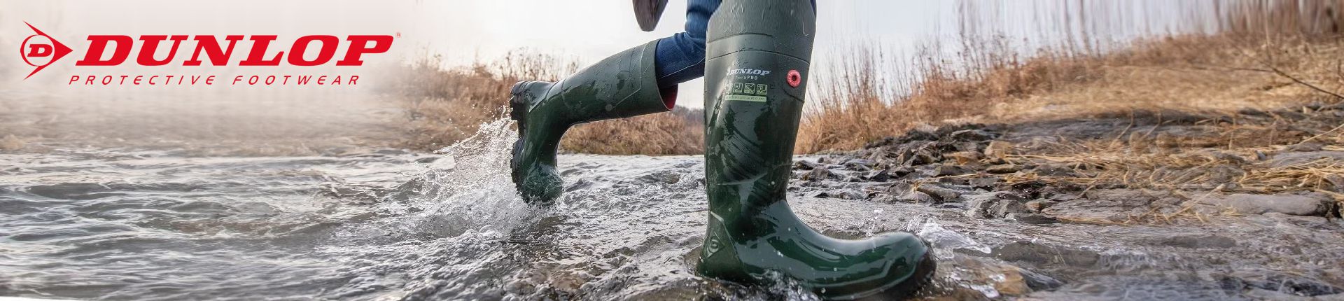 Bild Person in dunkelgrünen Dunlop Sicherheitsstiefeln beim Durchqueren eines kleinen Bachlaufs