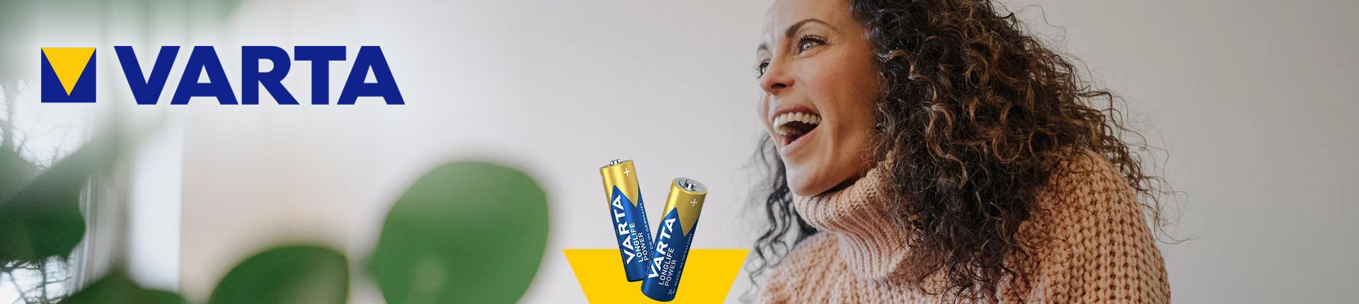 Bild Zwei Varta Consumer Batterien neben einer jungen lachenden Frau mit brauen langen lockigen Haaren