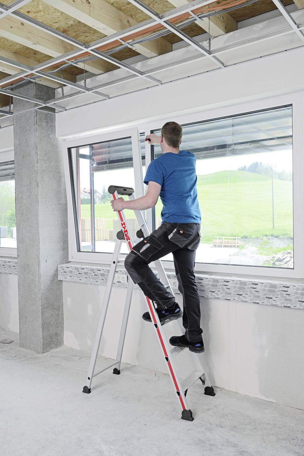  Fensterbauer in einem Rohbau bei der Montage auf einer Hymer Stufenstehleiter Plattform einseitig 5 Stufen Modell 402605 stehend bild 3