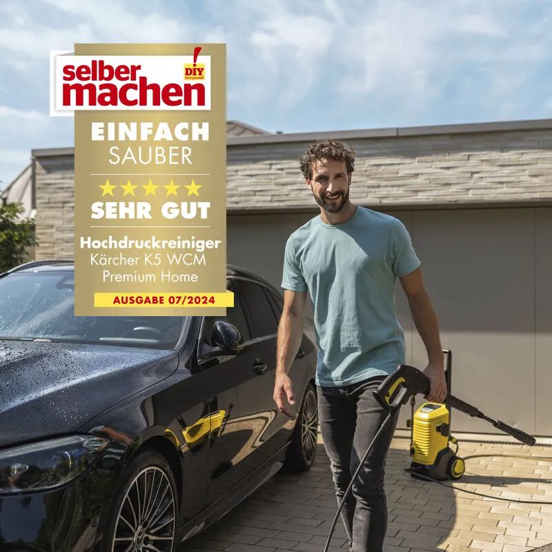 Ein Mann läuft mit einem Kärcher K5 WCM Premium Home Hochdruckreiniger über den Hof auf dem ein schwarzes Auto geparkt ist bild 2