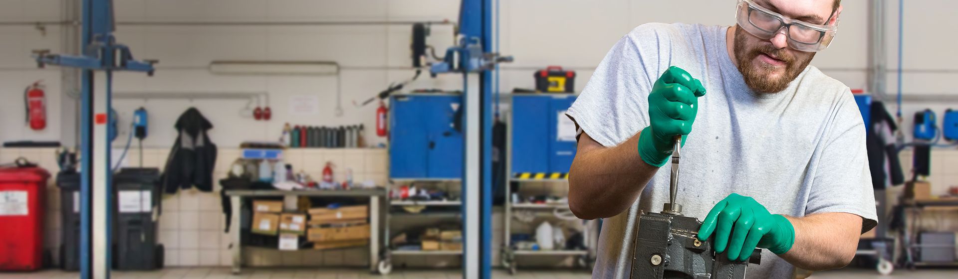 Junger Mann in einer Werkstatt mit grünen Einweghanschuhen von Ansell bei handwerklichen Arbeiten bild