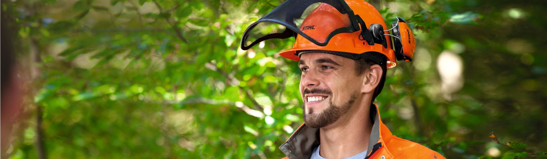 Junger Mann mit Stihl Schutzhelm mit Gehörschutkapseln und hochgeklapptem Visier bild