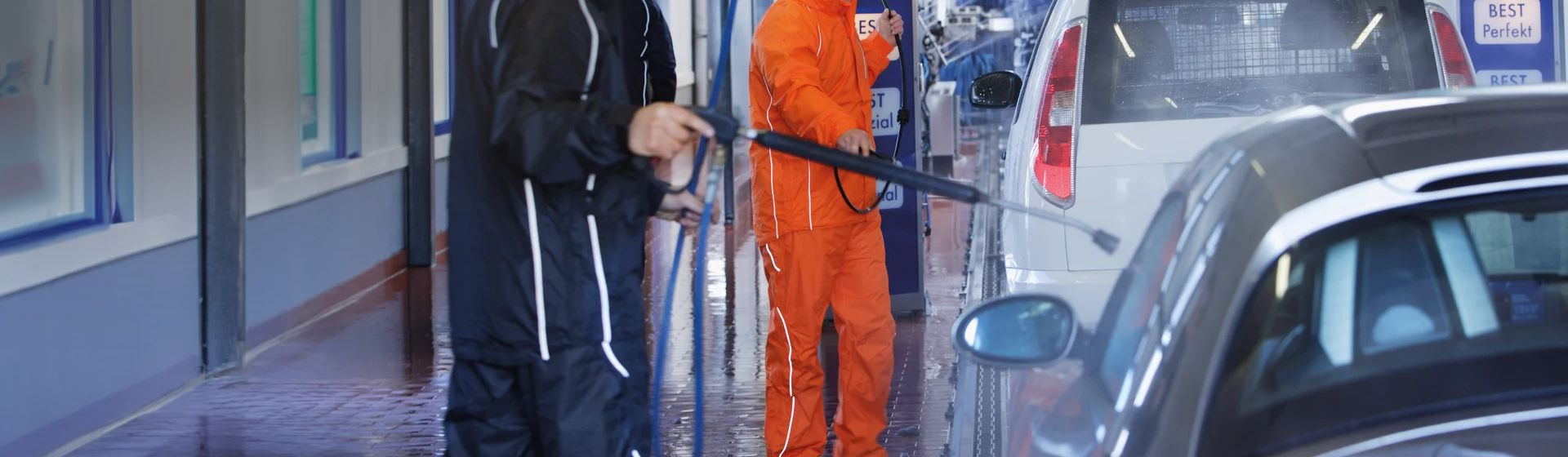 Zwei Männer in Regenhosen in einer Waschstraße bild