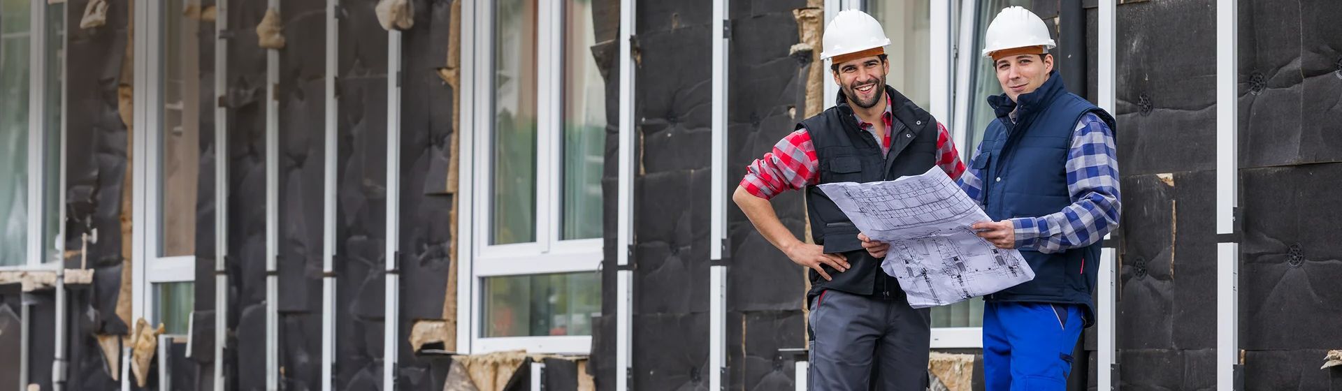 Zwei junge Handwerker in Arbeitkleidung mit karierten Hemd auf einer Baustelle bild