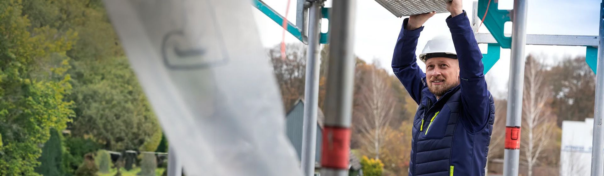 Handwerker auf einem Gerüst  in einer dunkelblauen Softshell Jacke von Planam bild