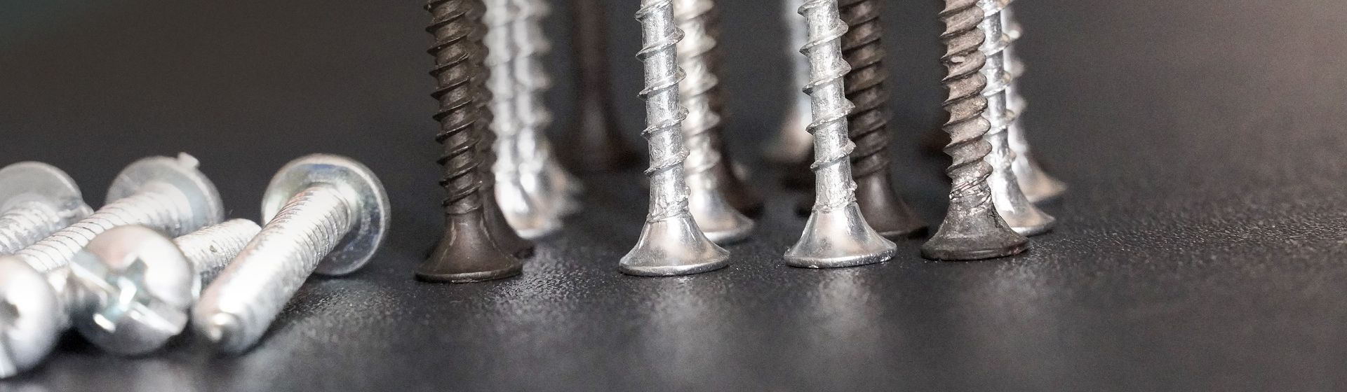 Köpfe verschiedener silberfarbener und schwarzer Schrauben stehend in Nahaufnahme bild