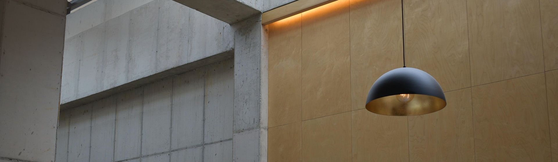 Schwarz-goldene Pendelleuchte in der Eingangshalle eines hohen Gebäudes hängend bild