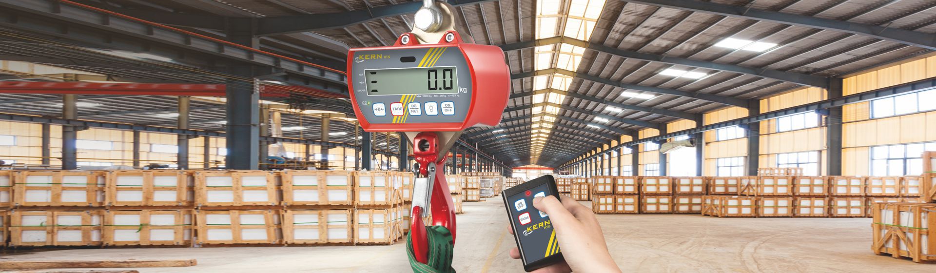 Rote Kern Hängewaage in Nahaufnahme, im Hintergrund eine Lagerhalle bild