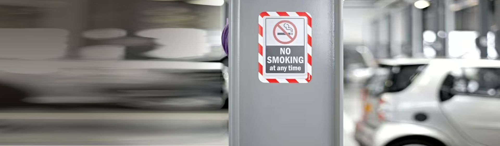 Rot-weiß gerahmte Sichttafel mit dem Hinweis "no smoking at any time" an einer grauen Betonsäule montiert bild