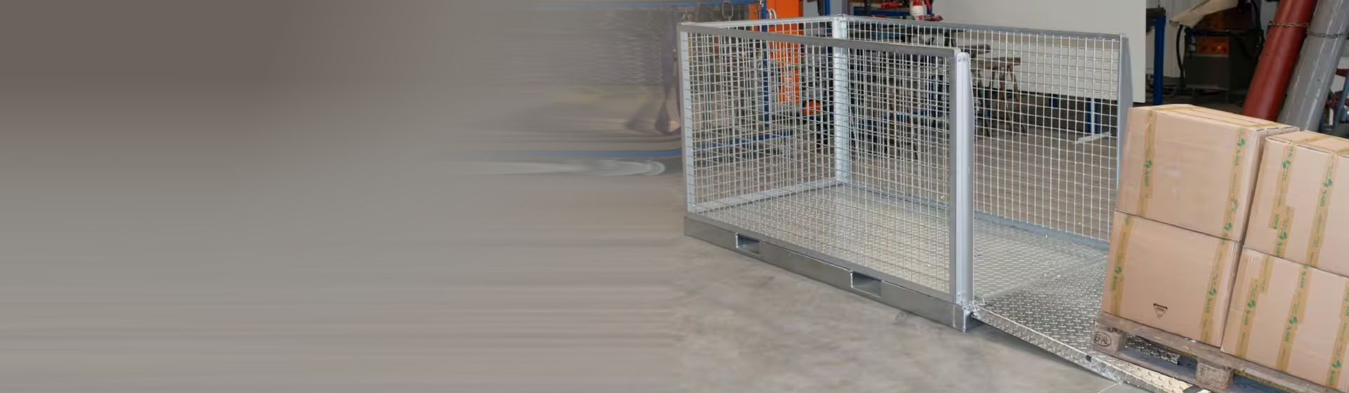Silberne Gitterbox aus Metall mit einer Beladerampe auf dem Boden eines Lagers stehend bild