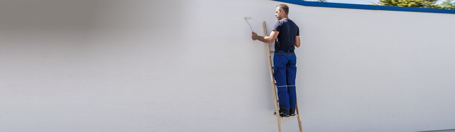 Maler auf einer Anlegeleiter beim Streichen einer Mauer bild