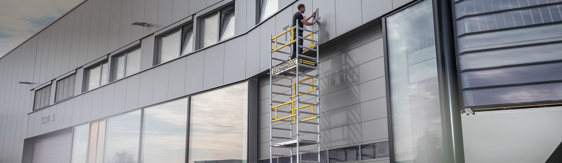Handwerker auf einem mobilen Gerüst bei Arbeiten an einem Firmengebäude bild