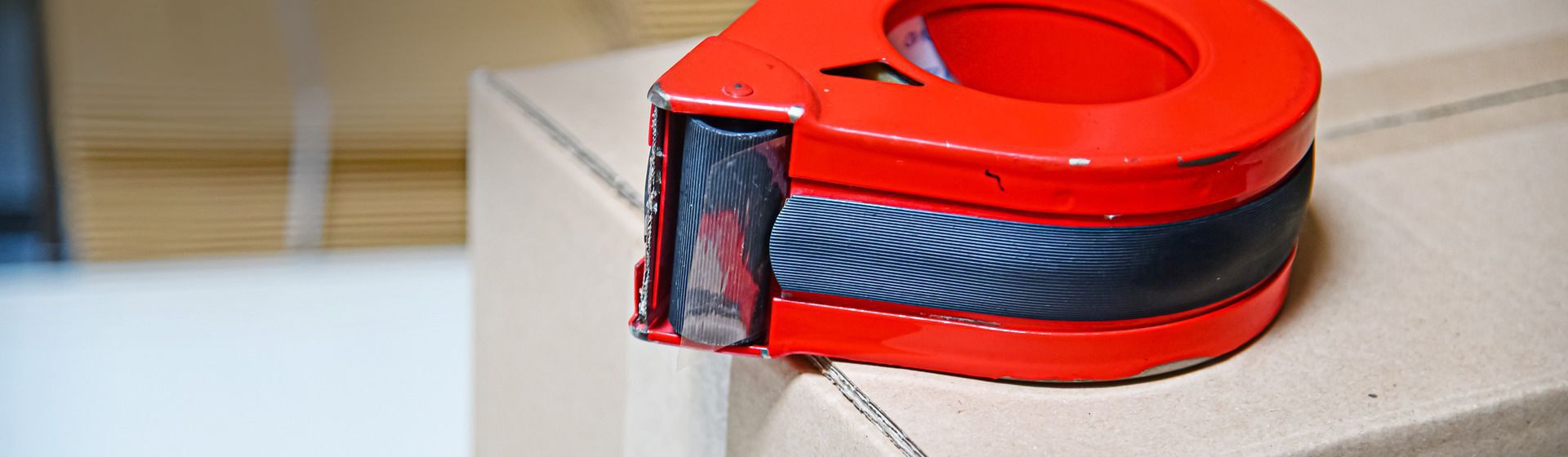 Roter Klebeband-Handabroller auf einem Paket liegend bild