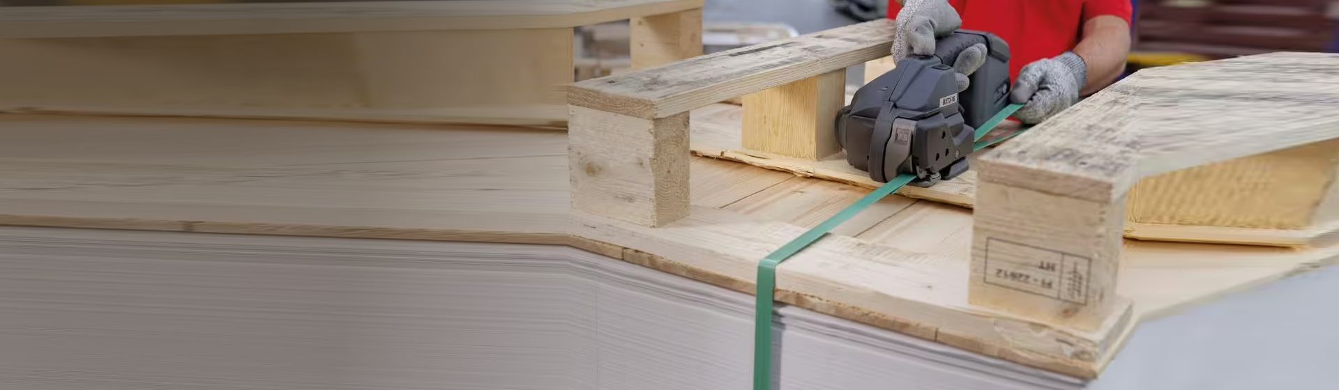 Grünes Kunststoffband wird mit einem Umreifungsgerät von Banholzer und Wenz an einer Palette angebracht bild