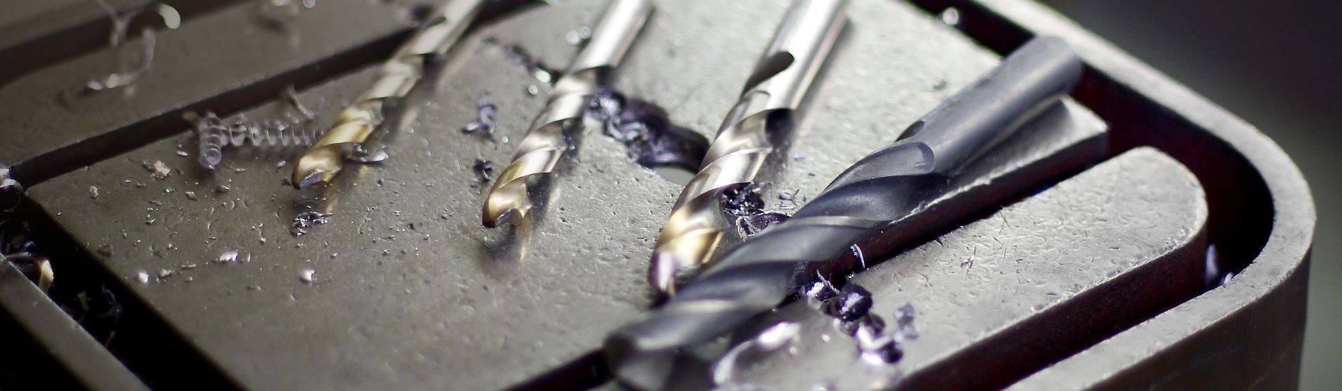 Vier Bohrer auf einer dunklen Metalloberfläche liegend bild