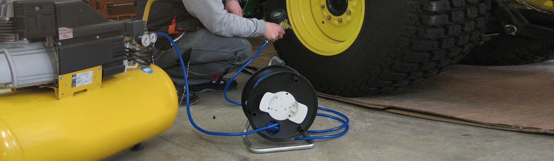 Brennenstuhl Druckluft Kabeltrommel in schwarz mit ausgerolltem blauen Kabel beim Befüllen eines Nutzfahrzeuge-Reifens mit Druckluft bild