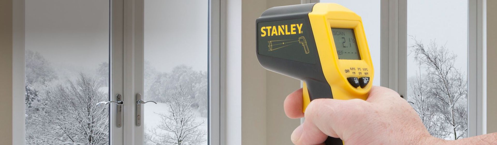 Digitales Infrarot Thermometer von Stanley bei der Temperaturmessung an einer Fensterfront bild