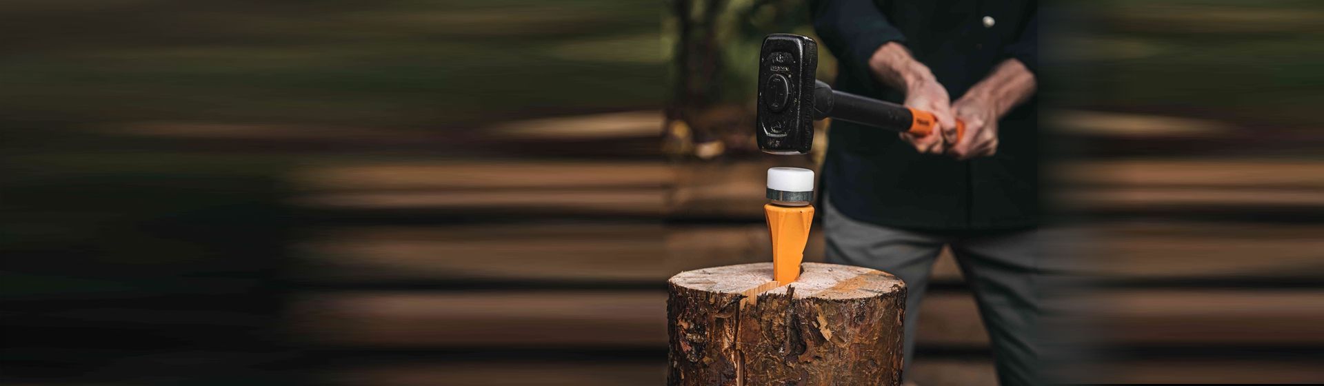 Orangefarbener Spaltkeil von Fiskars in einem Baumstumpf steckend bild