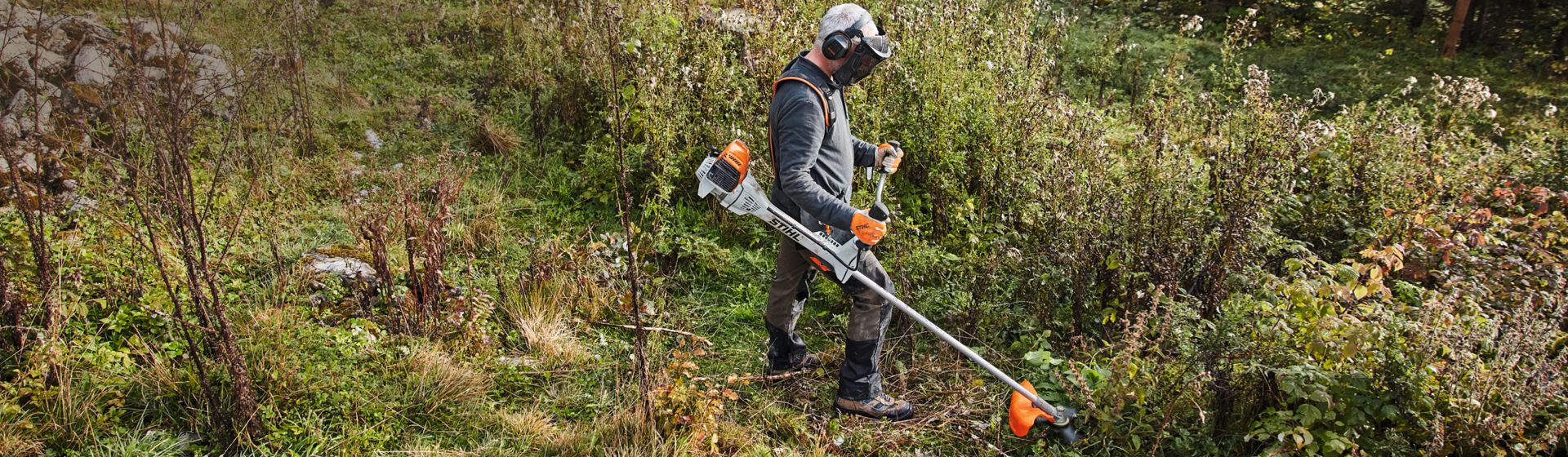 Mann mit Stihl Motorsense beim Mähen einer Wiese bild