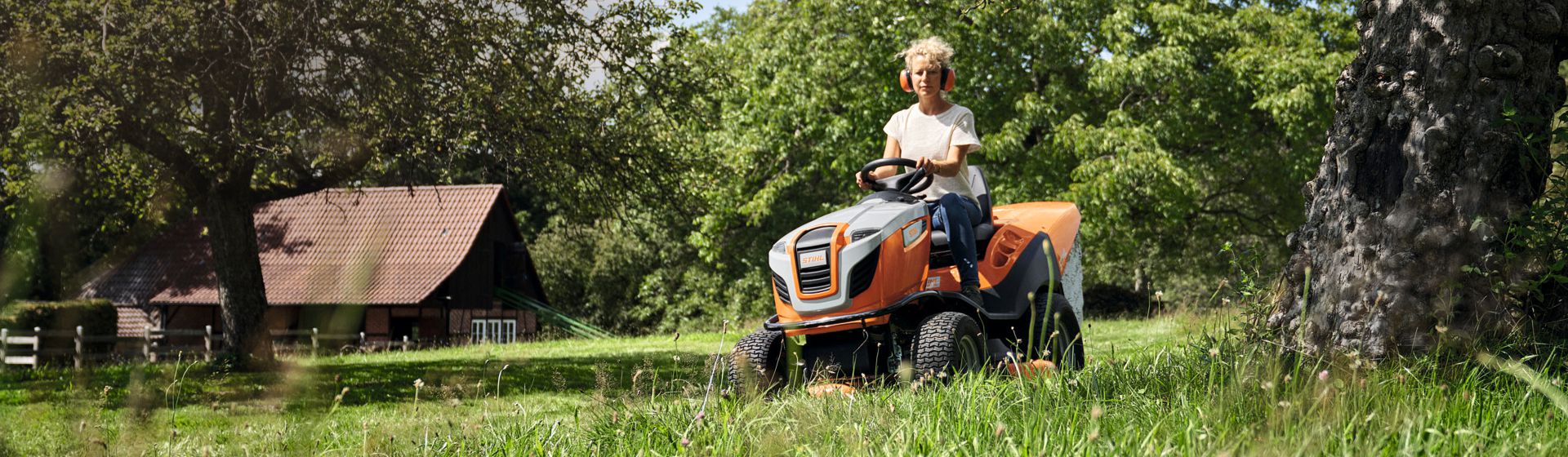 Frau auf einem Stihl Rasentraktor beim Mähen einer Wiese bild