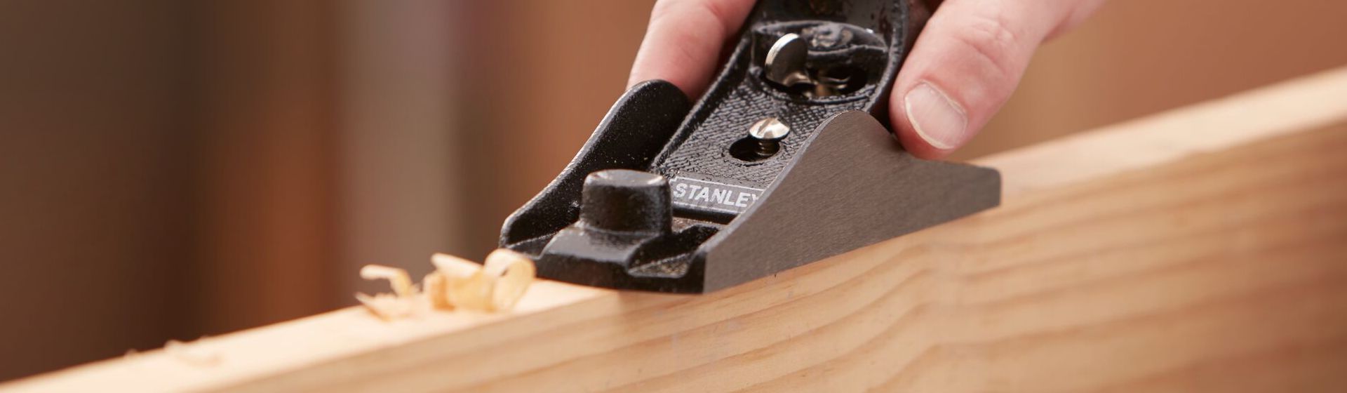 Schwarzer Einhandhobel von Stanley beim Bearbeiten einer Holzlatte bild