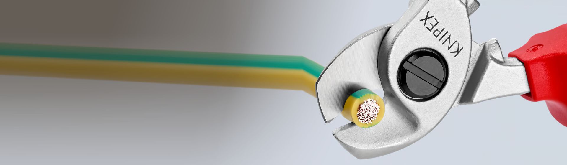 Knipex Kabelschere beim Abschneiden eines Kupferkabels mit gelb-grüner Ummantelung bild