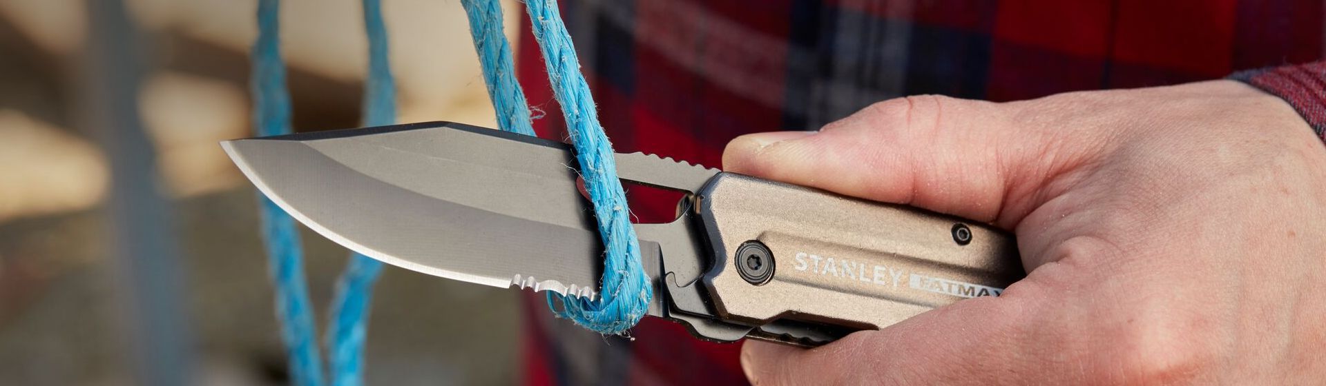 Silberfarbenes Taschenmesser von Stanley beim Durchtrennen eines blauen Stricks bild