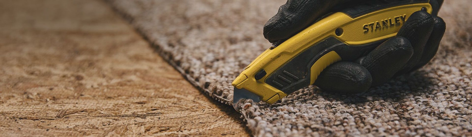 Gelbes Universalmesser von Stanley beim Schneiden eines Teppichbodens bild