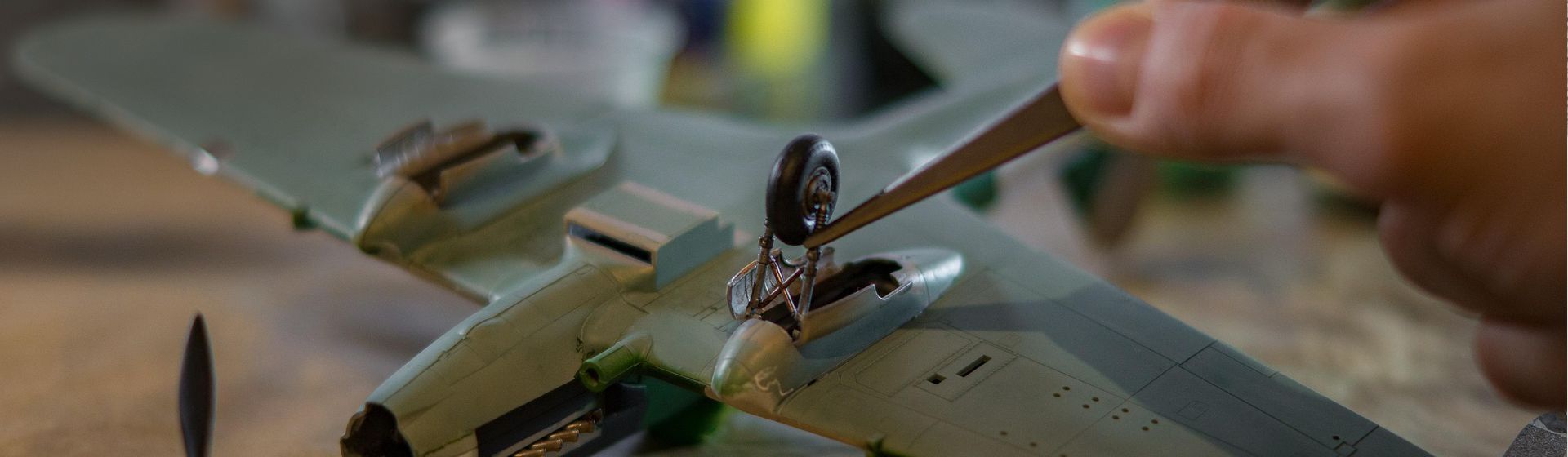 Befestigen eines Fahrwerks an einem auf dem Rücken liegenden Modellflugzeugs mit Hilfe einer Pinzette bild