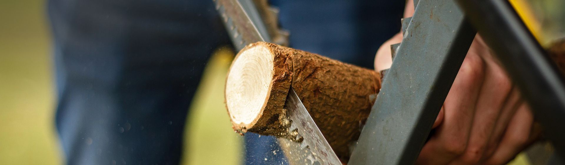 Handsäge beim Durchtrennen eines in einem Sägebock steckenden Astes bild