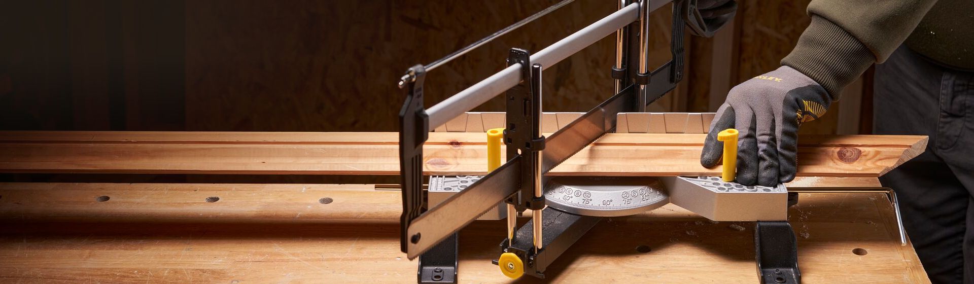 Mann beim Sägen einer Holzlatte in einem Gehrungsladekasten von Stanley bild