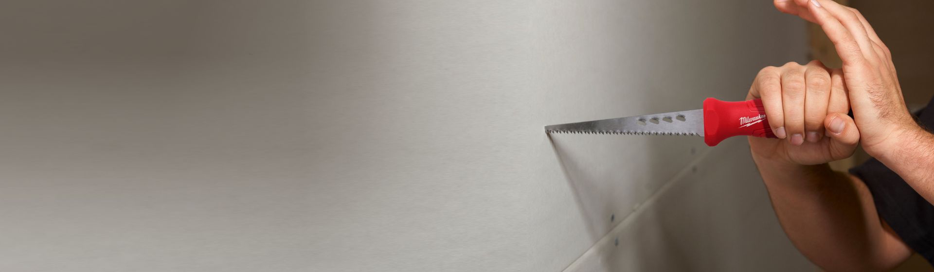 Mann bearbeitet eine weiße Gipskartonwand mit einer Stichsäge von Milwaukee bild