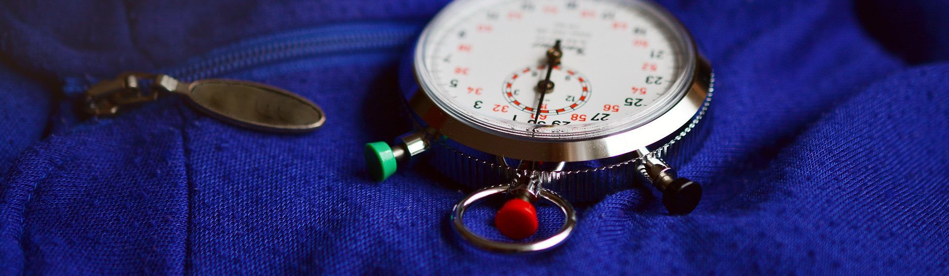 Runde manuelle Stoppuhr auf einem blauen Arbeitsoverall liegend bild