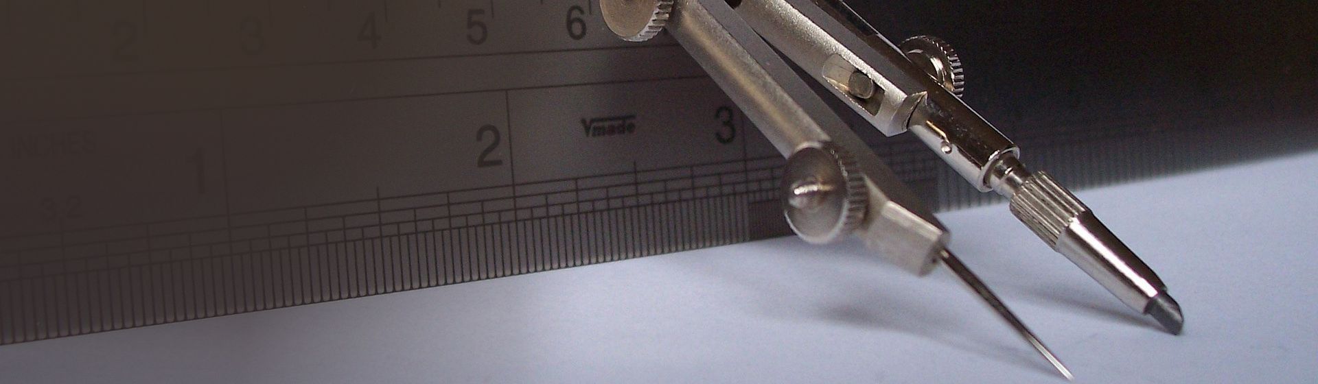 Silberfarbener Zirkel an einem Metall-Lineal angelehnt bild