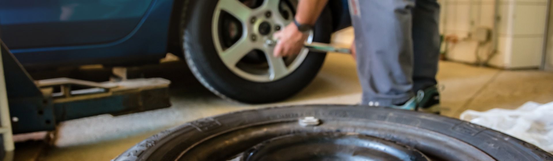 Mann beim Reifenwechsel an einem Auto in einer Werkstatt bild