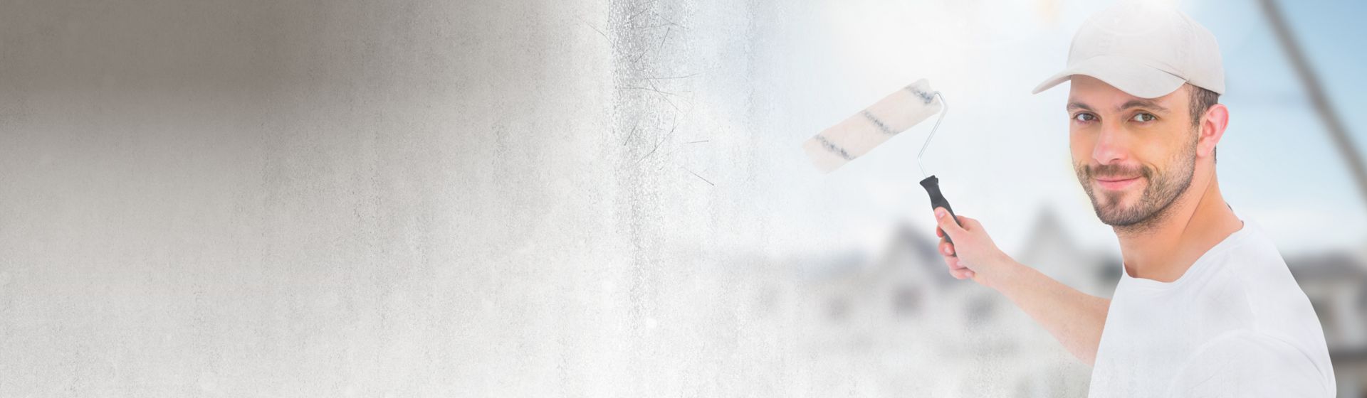 Junger Maler mit Farbrolle vor einer weiß-grauen Wand bild