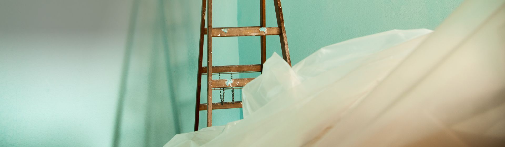 Weiße Maler-Abdeckfolie und Holzleiter in einem Raum bild