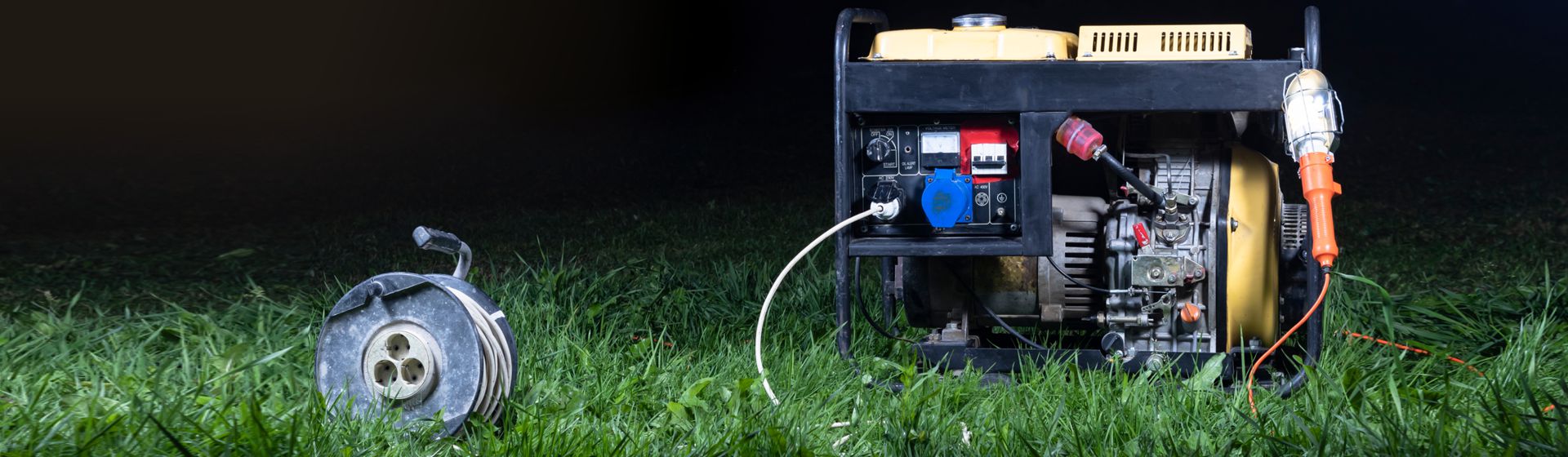 Stromerzeuger & Kabeltrommel auf einer Rasenfläche stehend bild