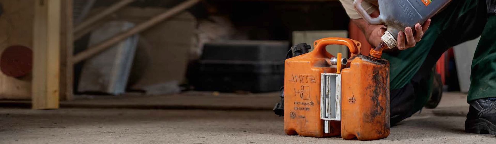 Mann befüllt einen orangefarbenen Kanister von Stihl mit Benzin bild