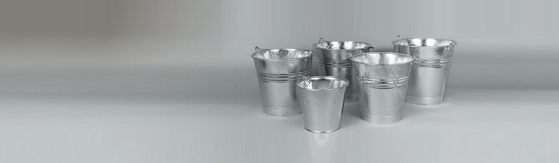 Fünf silberfarbene Metalleimer vor einem grauen Hintergrund bild