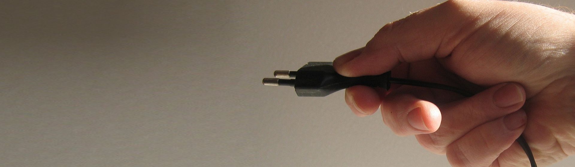 Schwarzes Netzkabel mit Schuko-Stecker in einer menschlichen Hand gehalten bild
